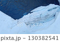 Young adult crossing snowy terrain near icy stream in winter adventure scene 130382541