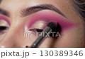 Applying vibrant pink and purple eyeshadow with a blending brush close up view	 130389346