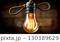 Hanging vintage light bulb illuminates a rustic space with warm glow and cord details in a cozy setting 130389629