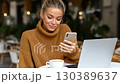 Young woman enjoying coffee while using smartphone at outdoor cafe in the morning 130389637