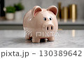 Simple ceramic piggy bank on a kitchen counter with a marble surface and blurred background elements 130389642