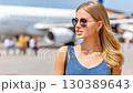 Woman in stylish sunglasses at the airport during daytime, blending fashion with travel excitement and adventure 130389643
