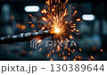 Spark from metalworking tool creates bright explosion of light in workshop during evening hours 130389644