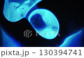 Fluid texture. Liquid mix. Defocused blue neon color water drop glow paint ink dark black flow oil blob floating on abstract light background. 130394741