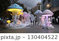 A group of people walking down a street next to a bunch of jellyfish 130404522