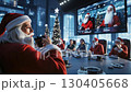 A woman in a santa claus outfit sitting at a table in front of a group of people 130405668