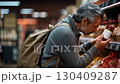 A man carefully inspecting a product label while shopping in a grocery store aisle filled with various packaged foods. 130409287
