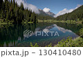 Serene mountain lake reflecting pine forest and sky, peaceful nature scene 130410480