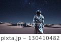Astronaut in metallic suit standing in desert under starry night sky. Futuristic exploration 130410482