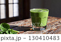 Green smoothie in glass on rustic wooden table in sunlight. Healthy lifestyle drink 130410483