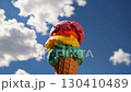 Triple scoop ice cream cone against blue sky with clouds. Summer dessert concept 130410489