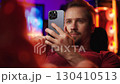 Man swiping on smartphone relaxing in cyberspace home office 4K 130410513
