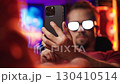 Man with anime glowing glasses swiping on smartphone 4K 130410514