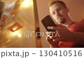 Low angle view of man swiping on smartphone beside a merchandise glass cabinet 130410516