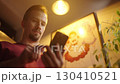 Low angle view of man swiping on smartphone beside a anime maid girls poster 4K 130410521