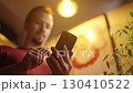 Low angle view of man swiping on smartphone beside a anime maid girls poster 4K 130410522
