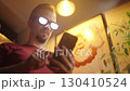 Man with anime glowing glasses swiping on smartphone 4K 130410524