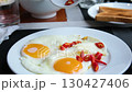 fried eggs chili pepper Pouring ketchup over open sandwich made with egg, cheese and sausages on slate 130427406