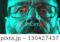 A focused individual gazing intently at digital data displayed on glasses, illuminated by a captivating neon blue-green light. 130427437