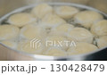 Cooking dumplings in boiling water with a slotted spoon on a stovetop in a modern kitchen environment 130428479