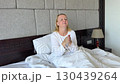 woman applying cream on face and hands happy sitting on bed taking care of herself morning hotel adults white bed european middle aged woman smile 130439264