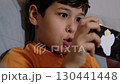 A boy, focused on his smartphone, reacts with enthusiasm during a game session on the couch. The moment reflects the emotional engagement of children with interactive digital media. 130441448