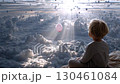 Blond toddler releasing pink balloon while sitting on soft blanket, sunlight filtering through clouds with distant hot air balloons floating peacefully 130461084