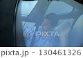 Male businessman reflecting in panoramic roof of modern electric car during browses mobile phone. Young entrepreneur using phone while riding on electrical auto with autopilot at urban road. Close up 130461326