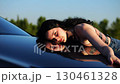 Beautiful smiling girl bought new electrical vehicle and hugging hood auto. Happy young woman enjoying modern electric automobile. Concept of buy or rent car. Slow motion 130461328