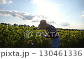 Female agronomist exploring plants at yellow meadow. Adult farmer examining ripe sunflowers at field on sunny day. Beautiful scenic landscape. Concept of agriculture and agronomy business. Close up 130461336