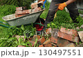 A bricklayer puts bricks in a cart.  130497551