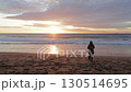 A woman approaches the seashore and looks at the sunset. 130514695