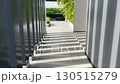 Modern architectural walkway with vertical steel beams casting rhythmic shadows on the ground, creating contemporary geometric design and artistic perspective, ideal for real estate, architecture 130515279