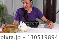 A woman holds a black domestic mini rabbit by the ears. 130519894