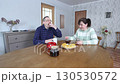 Mature couple enjoys breakfast with tea and cake at an oval dining table. 130530572