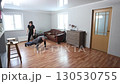 Holding partner legs for wheelbarrow walk, middle aged white woman in sportswear and mature man in homewear exercising together on wooden floor. 130530755
