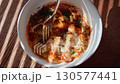 Fork mixing eggs in sauce with herbs, spicy texture blends into vibrant dish, spicy flavor highlights cooking process, spicy moment adds dynamic feel, perfect for culinary or lifestyle content 130577441