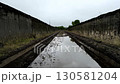 Water evaporating from a muddy road between concrete walls 130581204