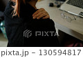 Hands rubbing aching shoulders in office setting with laptop and work equipment nearby 130594817