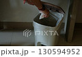 Asian woman hand throwing garbage into trash can symbolizing cleanliness and waste management 130594952