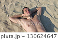 Man relaxing on beach sunbathing 130624647