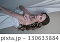 Portrait of a beautiful brunette with long hair on a fabric background in the studio. Beautiful natural woman posing for the camera 130633884