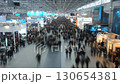 This overhead shot captures a bustling scene at a trade fair, filled with countless attendees exploring the various stands and exhibitors within the expansive hall. 130654381
