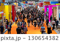 Busy trade show with attendees navigating the bustling convention center, filled with booths and displays, highlighting commerce and industry. 130654382