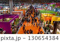 A vibrant trade show showcases booths and attendees, filled with energy and commerce. The event promotes networking and industry presence. 130654384
