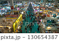 A bustling marketplace overflows with vendors and customers, showcasing the vibrant commerce and trade in this crowded exhibition hall. 130654387