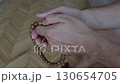 Close-up of a man's hands gently holding and counting wooden prayer beads. Conveys themes of 130654705