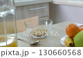 Close-up of a person's hands steams oatmeal with boiling water into a glass bowl with other fruits 130660568