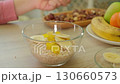 Close-up of a child hands adding nuts to a bowl of oats for a healthy breakfast. Emphasizes wellness 130660573