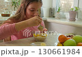 smiling girl sits at a kitchen table with a bowl of oatmeal, a pitcher of orange juice, and a plate 130661984